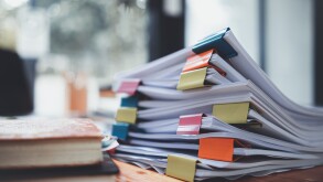 The stacks of documents lying on the desk are waiting to be verified before being sent to the Board of Directors to use the correct information before meeting with businessmen and investors.