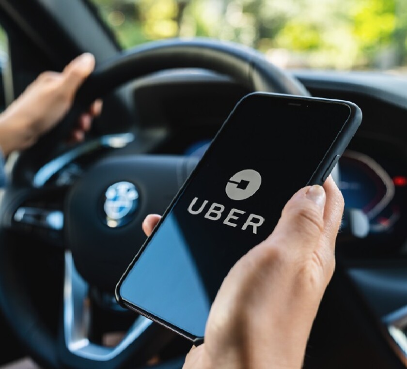 BERLIN, GERMANY JULY 2019: Uber driver holding smartphone in car. Uber is an American company offering transportation services online. Illustrative editorial.