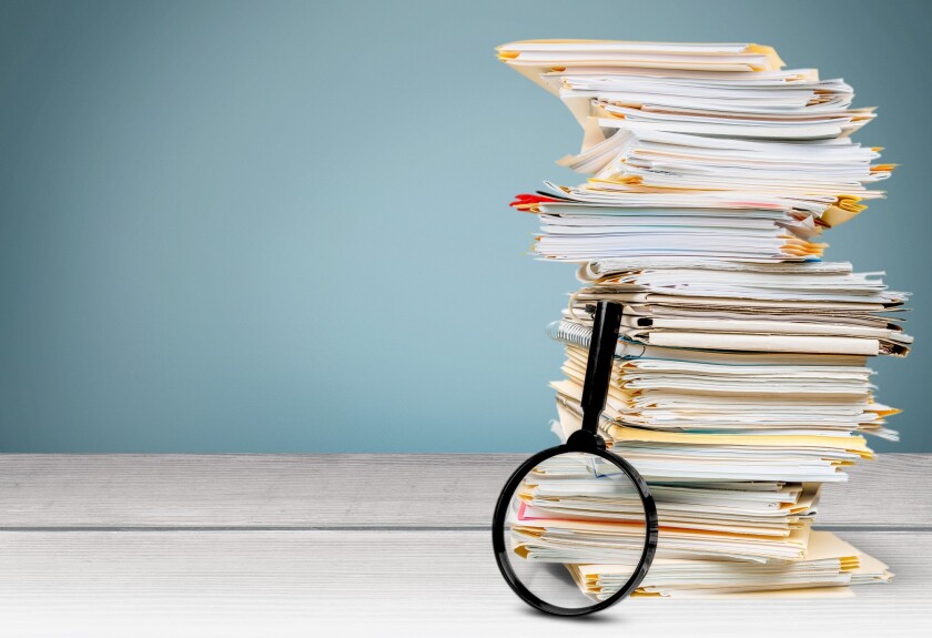 File folders with documents and magnifying glass on the desk