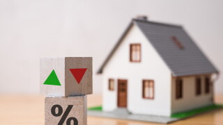 Wooden blocks percentage sign, arrow up and down with house model background. Central bank FED control interest rate increase or decrease effect to house price, monthly payment, buying home concept.
