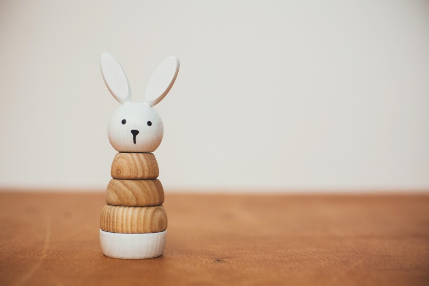 Stylish wooden toy for child on wooden table. Modern  wooden bunny pyramid with rings. Eco friendly, plastic free toys for toddler. Space for text