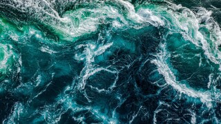 Abstract background. Waves of water of the river and the sea mee