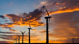 Big wind turbines in the desert at sunset background