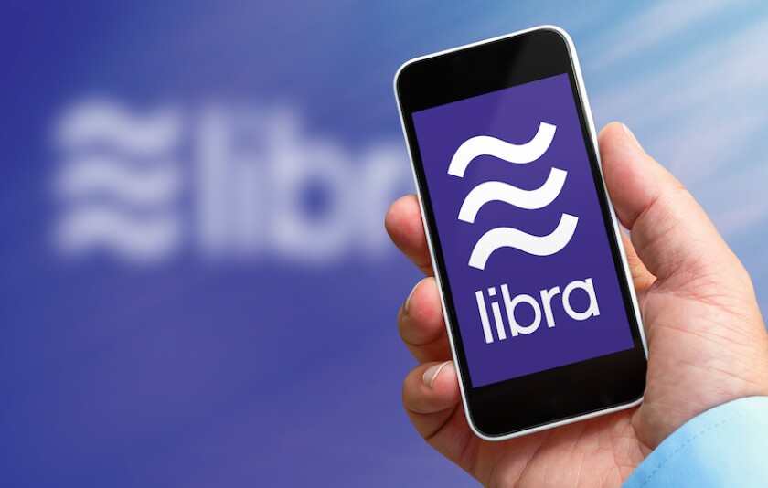 Man holding a smartphone in his hand with the libra logo, the new crypto currency created by facebook company
