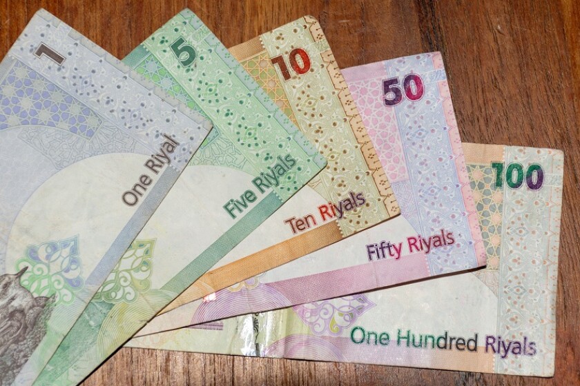 A close up of the  currency of Qatar or  the Qatari Riyal notes of cash spread out on the white background. Money exchange.