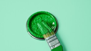 green paint in a paintbrush and lid of a paint can