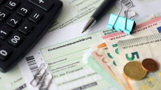 German income tax return form with pen and european euro money bills lies on accountant table close up. Taxpayers in Germany using euro currency to pay taxes