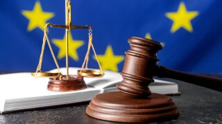 Gavel of judge with scales of justice and book against European Union flag