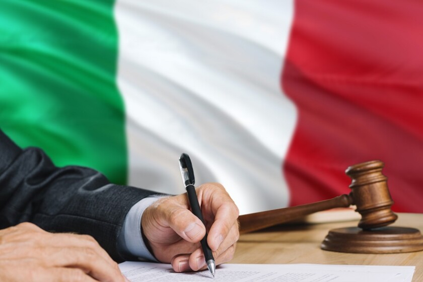Judge writing on paper in courtroom with Italy flag background. Wooden gavel of equality theme and legal concept.