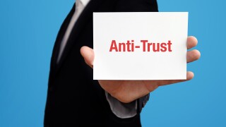 Anti-Trust. Geschäftsmann im Anzug hält Karte in die Kamera. Der Begriff Anti-Trust steht im Schild. Symbol für Business, Finanzen, Statistik, Analyse, Wirtschaft