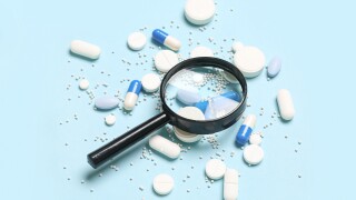 Magnifier with pills on blue background