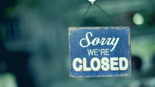 Blue closed sign in the window of a shop displaying the message "Sorry we are closed"