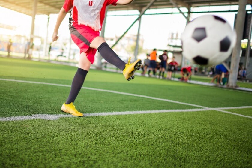 blurry ball after boy soccer player speed run on green artificia