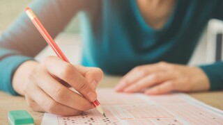 Female student holding pencil and examination paper