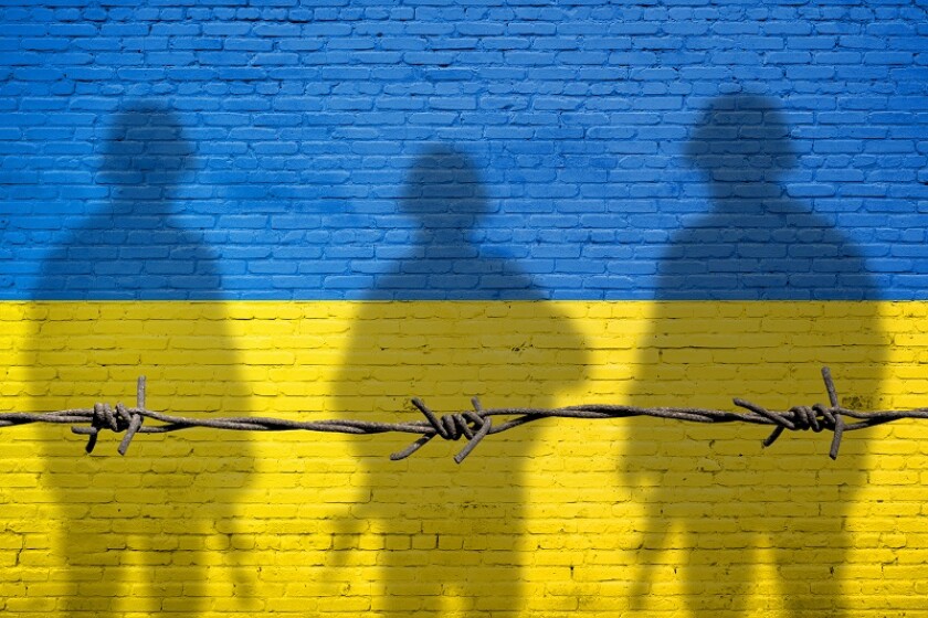 Flag of Ukraine painted on a brick wall with soldiers shadows. R