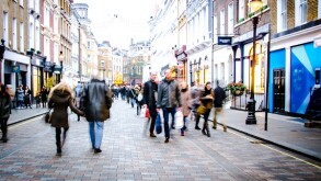 Motion blurred people on busy city street of shops