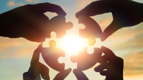 Four hands of businessmen put together a puzzle against the back