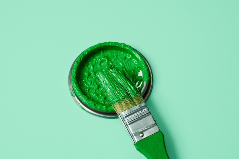 green paint in a paintbrush and lid of a paint can