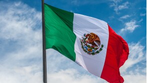 Flag of Mexico over blue cloudy sky