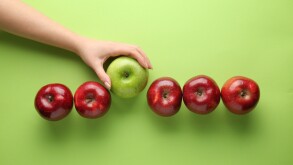 Female hand with tasty apples on color background. Concept of uniqueness