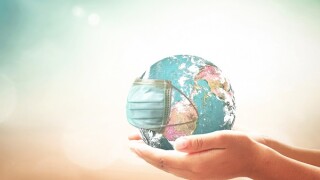 COVID-19 prevention concept: Human hands holding earth globe with medical disposable face mask. Elements of this image furnished by NASA