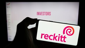 Stuttgart, Germany - 11-21-2023: Person holding mobile phone with logo of consumer goods company Reckitt Benckiser Group plc in front of business web page. Focus on phone display.