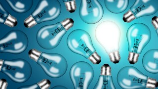 Lightbulbs on blue background with one lit