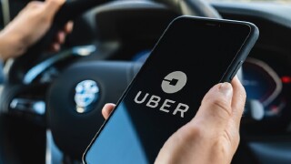BERLIN, GERMANY JULY 2019: Uber driver holding smartphone in car. Uber is an American company offering transportation services online. Illustrative editorial.
