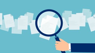 Employer with magnifying glass exploring application papers