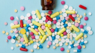 Colorful drug pills on blue background, pharmaceutical concept