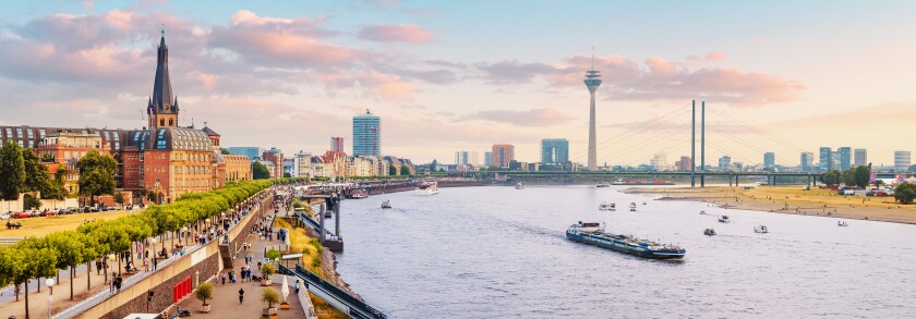 Urban panoramic cityscape view of Dusseldorf old town and transportation waterway of the whole of Germany - the Rhine River, along which large barges and small ships are sailing