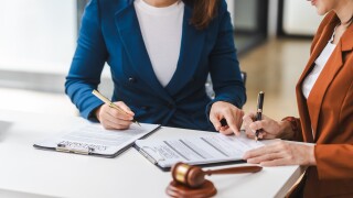 Two young and middle-aged Asian women lawyers in formal suits discuss legal contract, focusing on legislation and women's rights in law office.