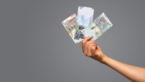 Beautiful female hands hold qatari rial on gray background. Copy space, gray background