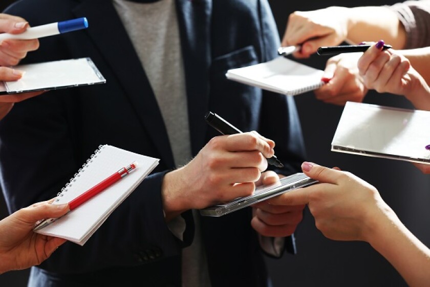 Elegant man signing autograph in notebook on dark background