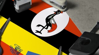 Uganda flag with office clerk workplace background. National stationary concept with office tools.
