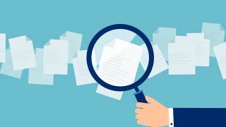Employer with magnifying glass exploring application papers