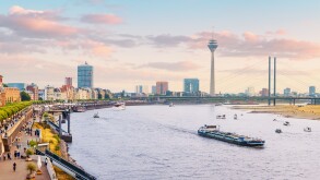 Urban panoramic cityscape view of Dusseldorf old town and transportation waterway of the whole of Germany - the Rhine River, along which large barges and small ships are sailing