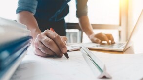 Image of engineer drawing a blue print design building or house, An engineer workplace with blueprints, pencil, protractor and safety helmet, Industry concept