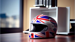 Red racing helmet with Union Flag (Jack) for motorbike scooters, sports and touring car driver in modern white office.