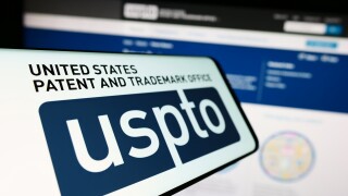 Stuttgart, Germany - 10-29-2023: Mobile phone with logo of agency United States Patent and Trademark Office (USPTO) in front of website. Focus on center-left of phone display.
