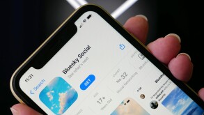 Lviv, Ukraine - 09 25 2023 : Twitter vs BlueSky. Twitter alternative Bluesky Social media in an App Store on an iPhone screen. Hand holding iPhone with Bluesky app on X twitter social media logo