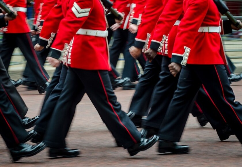 Queen's Royal Guard soldiers walking in red coat uniforms in mot
