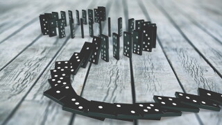 Black dominoes chain on a dark table. Domino effect concept