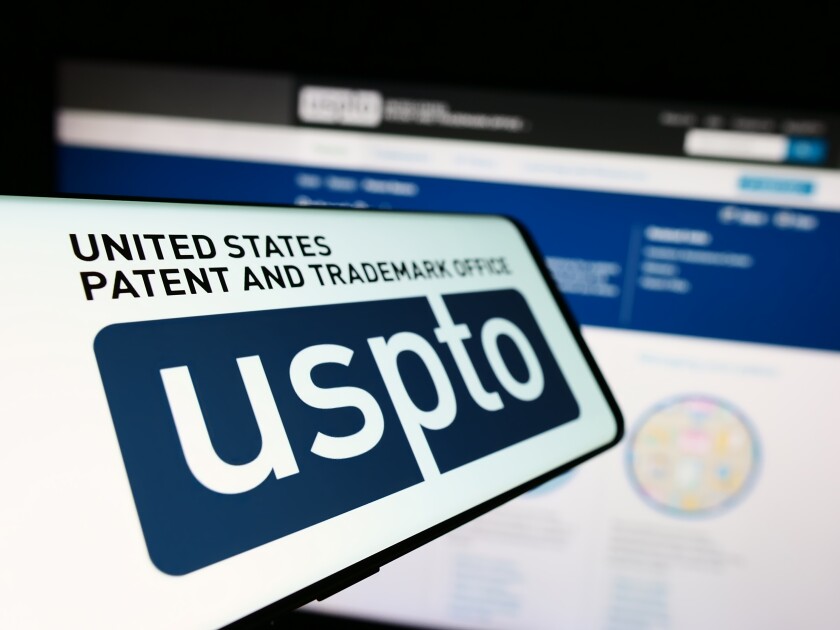 Stuttgart, Germany - 10-29-2023: Mobile phone with logo of agency United States Patent and Trademark Office (USPTO) in front of website. Focus on center-left of phone display.