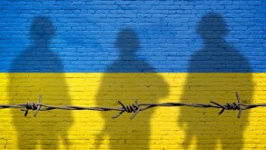 Flag of Ukraine painted on a brick wall with soldiers shadows. R