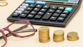 Financial planning concept with a calculator, coins, and a eyeglasses on the table.