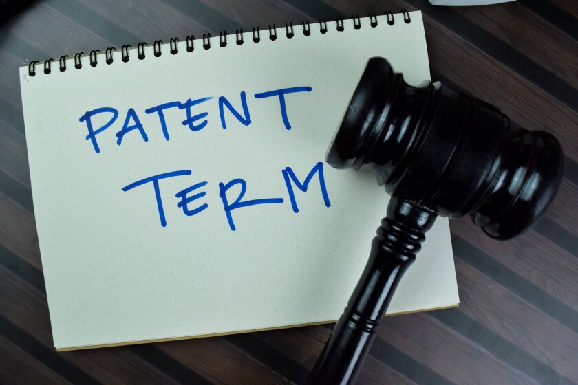 Concept of Patent Term write on a book with gavel isolated on Wooden Table.