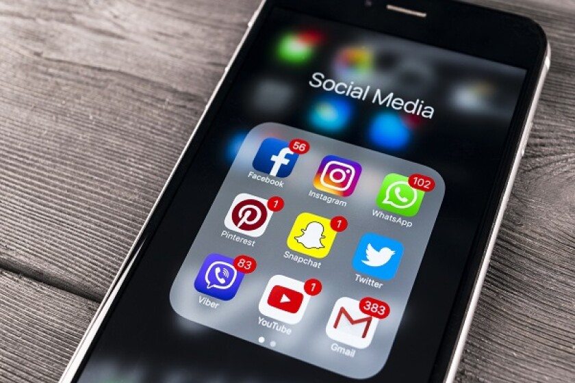 Sankt-Petersburg Russia November 11, 2017: Apple iPhone 7 on wooden table with icons of social media facebook, instagram, twitter, snapchat application on screen. Smartphone Starting social media app.