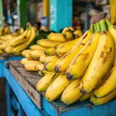 A fresh bundle of yellow bananas resting on a market stall with tropical leaves.