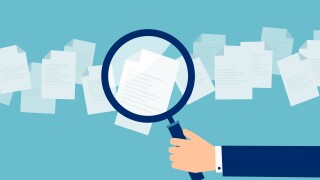 Employer with magnifying glass exploring application papers